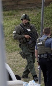 A police officer holds a rifle as he walks near the scene where a man is said to be holding four Gwinnett County firefighters hostage in Suwanee, Ga., Wednesday, April 10, 2013. (AP Photo/John Bazemore)