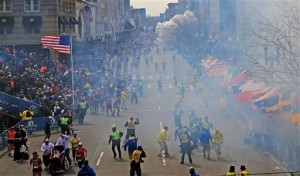 People react as an explosion goes off near the finish line of the 2013 Boston Marathon in Boston, Monday, April 15, 2013. Two explosions went off at the Boston Marathon finish line on Monday, sending authorities out on the course to carry off the injured while the stragglers were rerouted away from the smoking site of the blasts. (AP Photo/The Boston Globe, David L Ryan)