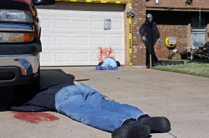 This Thursday, Oct. 17, 2013 photo shows Johnnie Mullins' controversial Halloween display featuring headless dummies dressed in his work clothes at his home in Mustang, Okla, In the display, one dummy lies under a truck with blood splattered on the driveway, foreground, and another along the blood-stained garage door. Mullins' wife, Jennifer, said she got the idea for the macabre scene from the social media site Pinterest. (AP Photo/Sue Ogrocki)