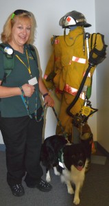 Janet Velenovsky and Oscar with a firefighter's turnout gear used for training.