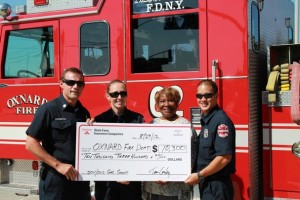 Oxnard Fire Department personnel, joined by City Councilmember Irene Pinkard, hoist an oversized check from State Farm signifying a grant that will help firefighters learn Spanish on iPads.